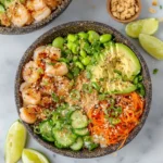 Colorful shrimp poke bowl with seasoned shrimp, avocado, cucumber, edamame, and spicy mayo served in a white bowl